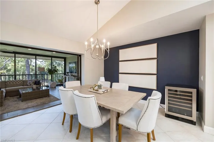 Dining room featuring wine cooler, vaulted ceiling, a chandelier, and light tile patterned floors
