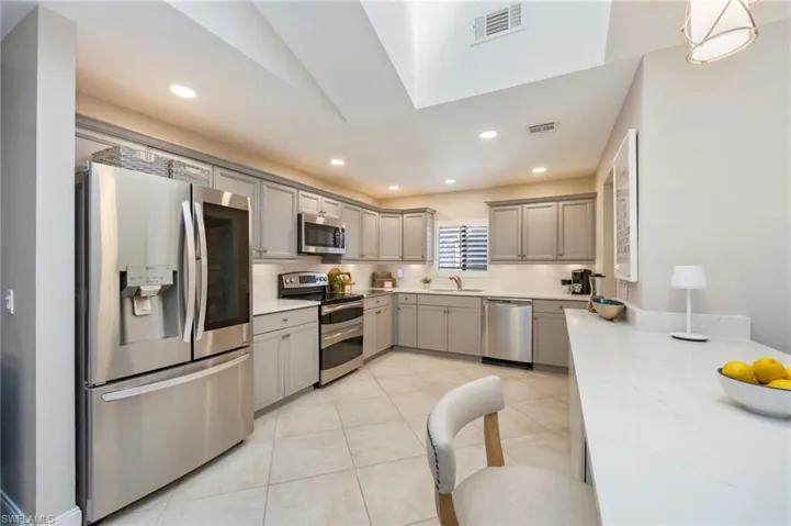 Kitchen featuring stainless steel appliances, gray cabinets, light tile patterned flooring, backsplash, and recessed lighting