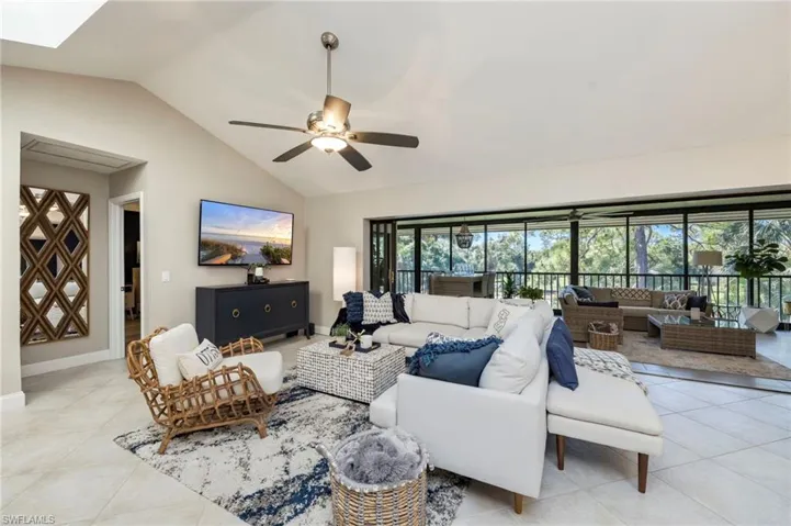 Living area featuring ceiling fan, light tile patterned floors, and a high ceiling