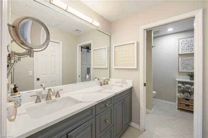 Bathroom with double vanity and light tile patterned flooring