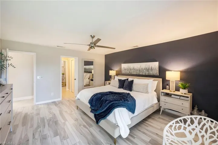 Bedroom featuring light wood-type flooring, a ceiling fan, and an accent wall