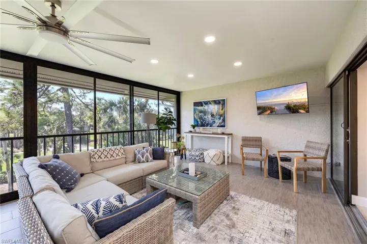 Sunroom featuring a textured wall, recessed lighting, floor to ceiling windows, and wood finished floors
