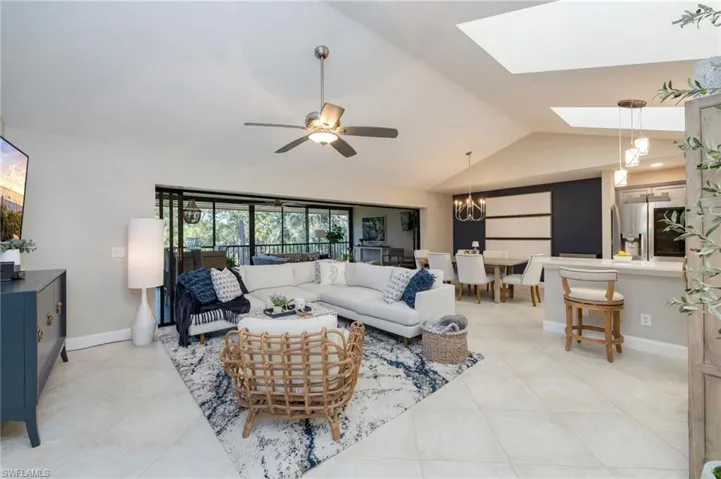 Living area with a skylight, a ceiling fan, suspended lighting, and light tile patterned flooring