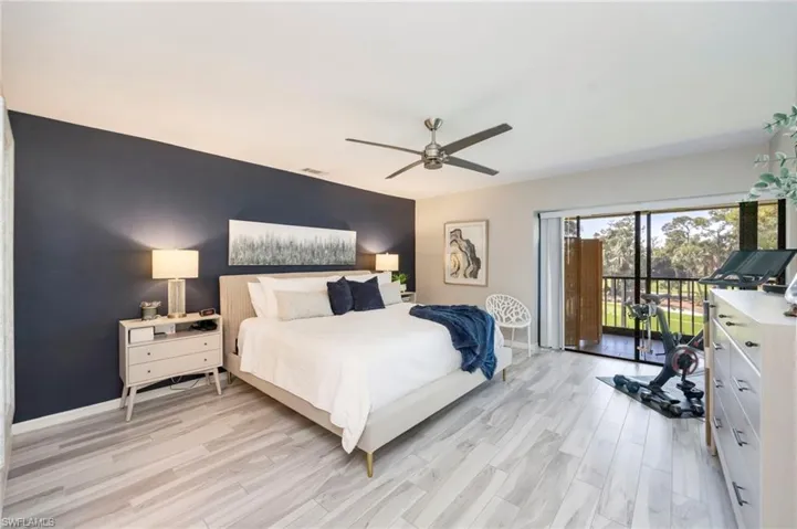 Bedroom with access to exterior, an accent wall, light wood-style floors, and ceiling fan