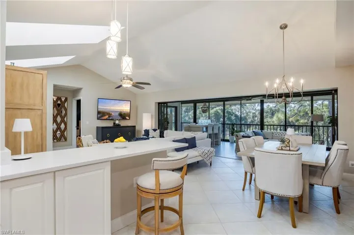 Kitchen with a skylight, lofted ceiling, open floor plan, suspended lighting, and light tile patterned floors