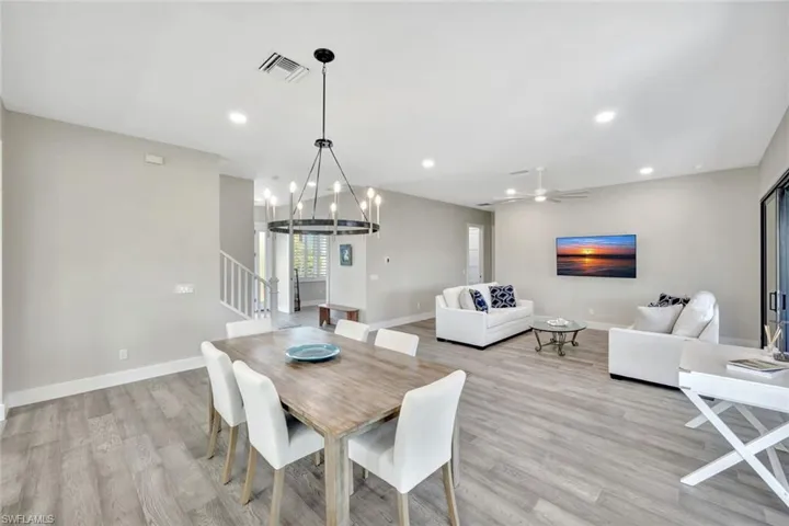 Dining space with recessed lighting, a ceiling fan, stairs, a chandelier, and light wood-style flooring