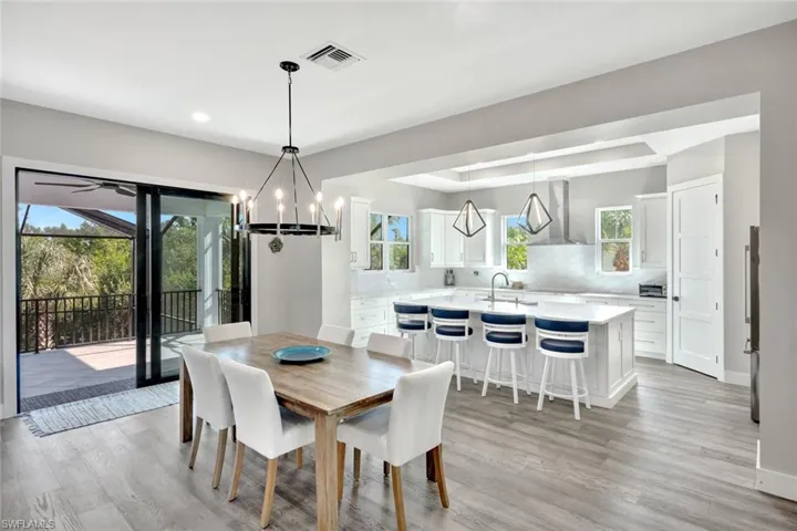 Dining area with light wood finished floors, a chandelier, recessed lighting, and a tray ceiling