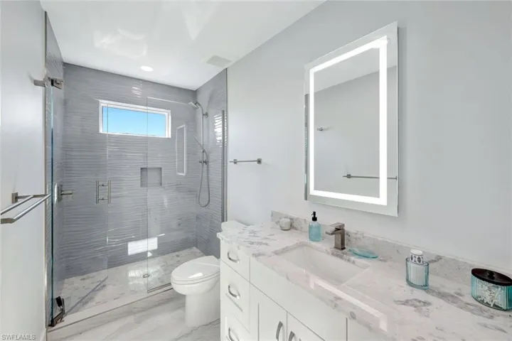 Full bath with a shower stall, vanity, and light marble finish flooring