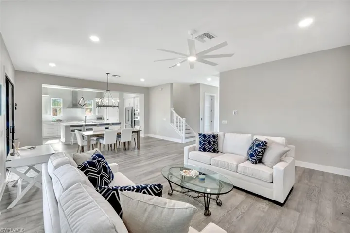 Living area featuring a ceiling fan, recessed lighting, stairs, light wood-style flooring, and a chandelier