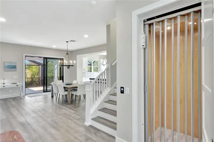Foyer entrance featuring light wood-type flooring, elevator, recessed lighting, and a chandelier