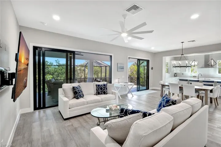 Living area featuring healthy amount of natural light, light wood finished floors, ceiling fan, recessed lighting, and a chandelier
