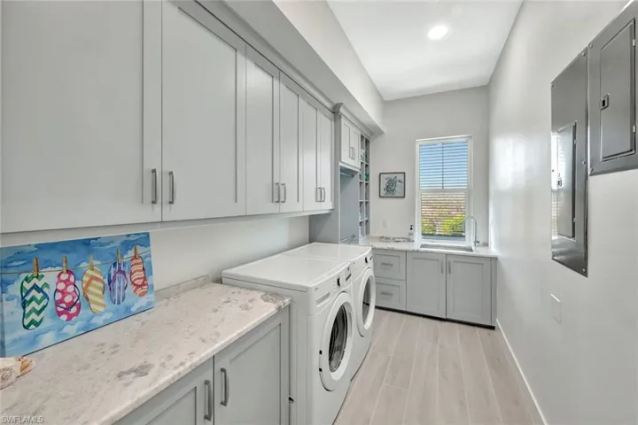 Laundry room with cabinet space, washing machine and clothes dryer, wood tiled floors, and electric panel