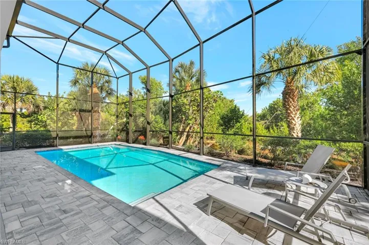 Outdoor pool featuring a sunroom, glass enclosure, and a patio