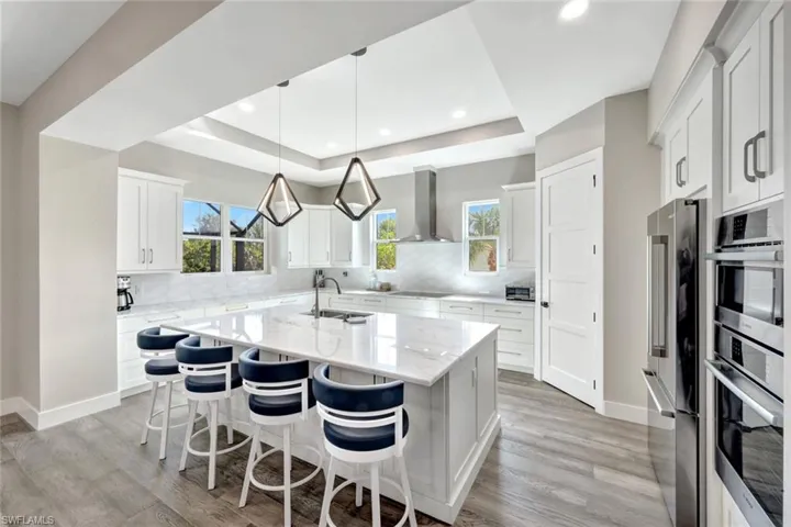 Kitchen with an island with sink, a kitchen breakfast bar, white cabinetry, a raised ceiling, and recessed lighting