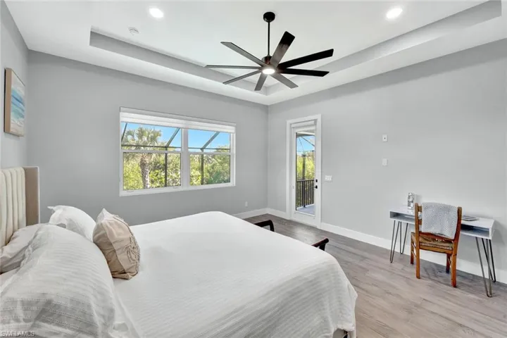 Bedroom featuring access to outside, a tray ceiling, a ceiling fan, recessed lighting, and light wood-style floors