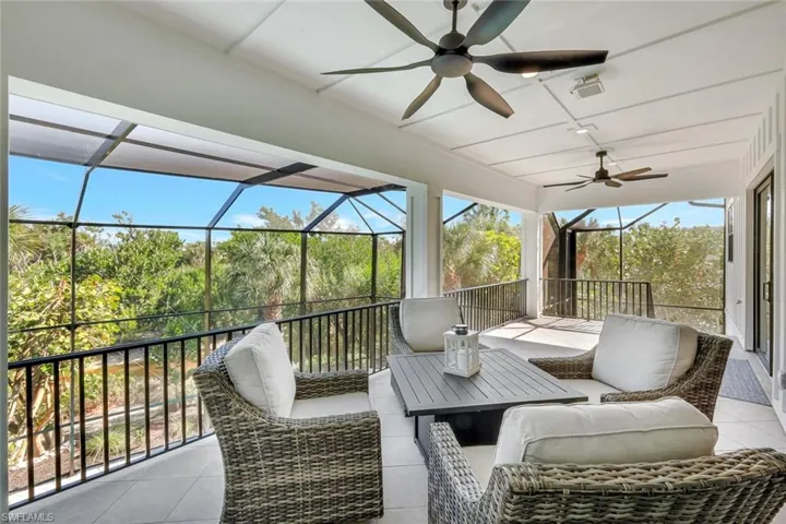 View of patio featuring a ceiling fan, a sunroom, and glass enclosure