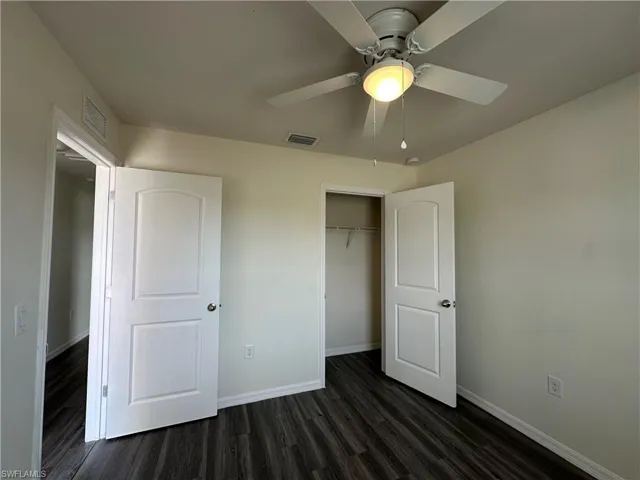 Unfurnished bedroom with dark wood-style flooring, a ceiling fan, and a closet