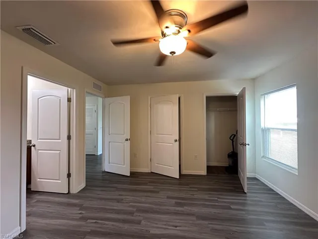 Unfurnished bedroom with ceiling fan, dark wood finished floors, and a closet