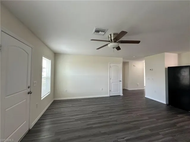 Unfurnished living room with dark wood-style flooring and ceiling fan