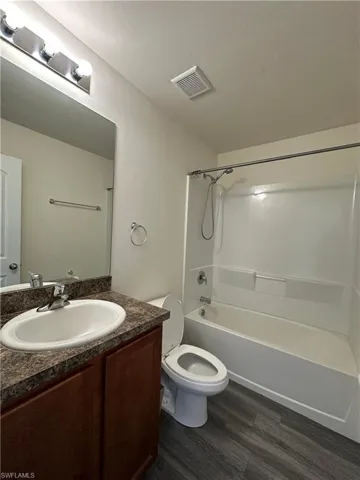 Full bath featuring shower / washtub combination, vanity, and dark wood-type flooring