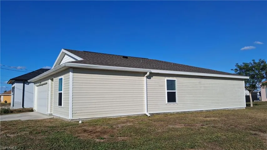 View of property exterior with a lawn, driveway, an attached garage, and roof with shingles