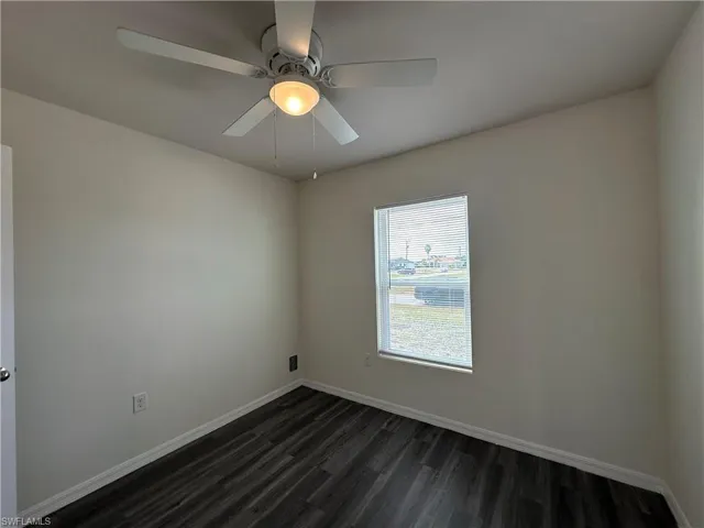 Spare room with dark wood finished floors and a ceiling fan