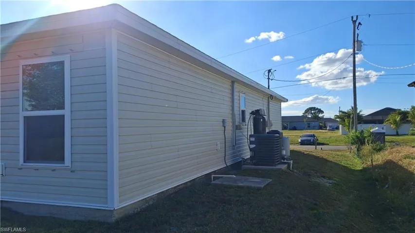 View of side of property with a lawn and a cooling unit