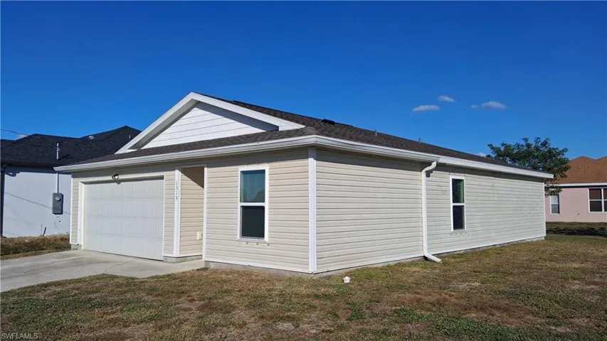 View of side of property featuring a yard, concrete driveway, and a garage