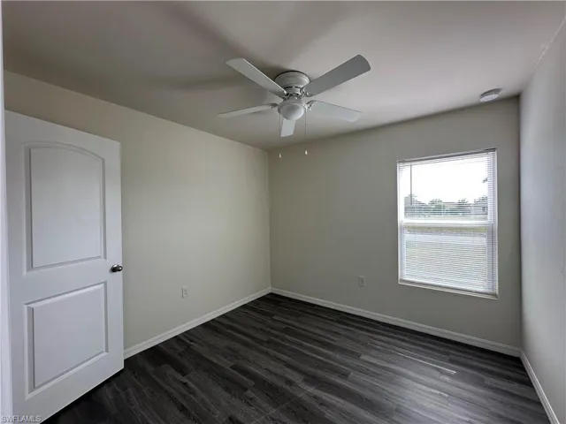 Unfurnished room with dark wood-style flooring and a ceiling fan