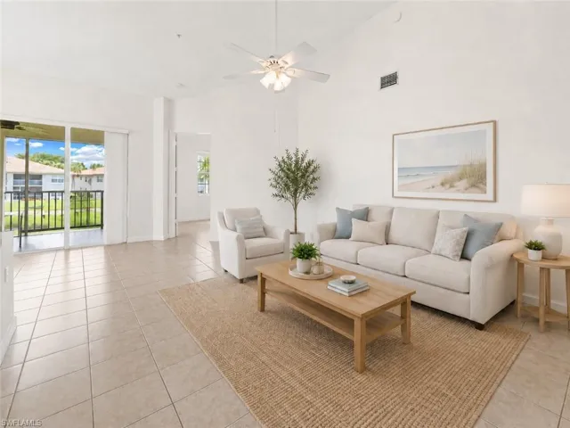 Spacious living area featuring vaulted ceilings, ceiling fan, and large format tile flooring