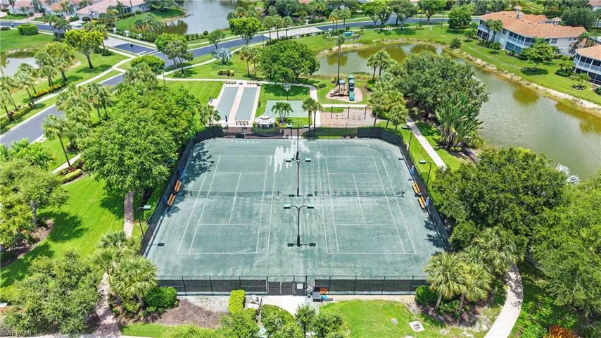 Community recreational amenities featuring two tennis courts with lighting, a bocce ball court, a covered gazebo, and a children's play structure, all surrounded by mature landscaping