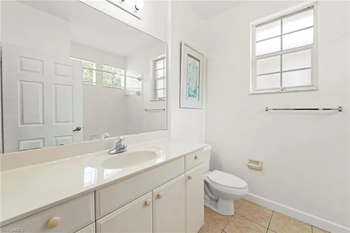 Bathroom featuring a spacious vanity with an integrated sink, ample counter space, white cabinetry with round knobs, and a large wall-mounted mirror