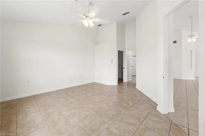 Spacious interior featuring neutral tile flooring, high ceilings, and a ceiling fan with integrated lighting