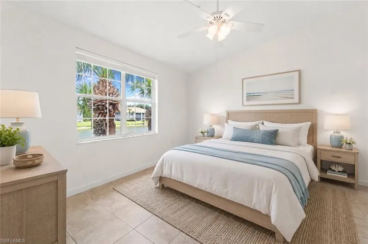 Vaulted ceiling bedroom featuring a large window with water and tropical foliage beyond