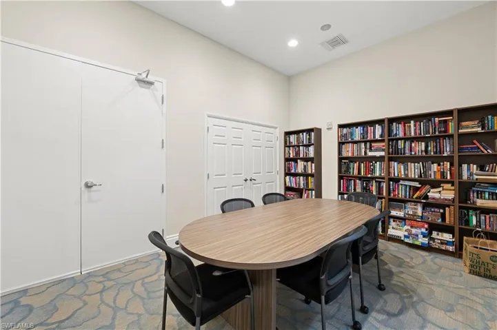 Collaborative room featuring a wood-finish oval table, integrated bookshelves, and patterned carpet flooring