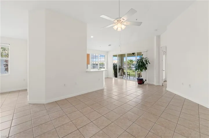 Spacious interior with tile flooring throughout, featuring a vaulted ceiling and a ceiling fan