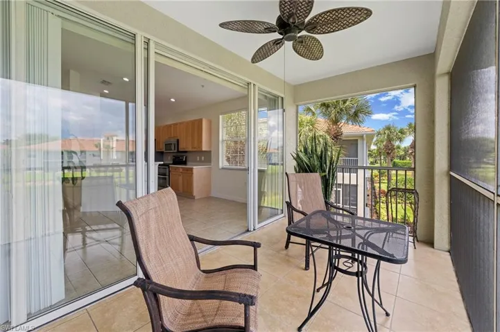 Screened balcony with tile flooring, ceiling fan, and sliding glass door access to the interior