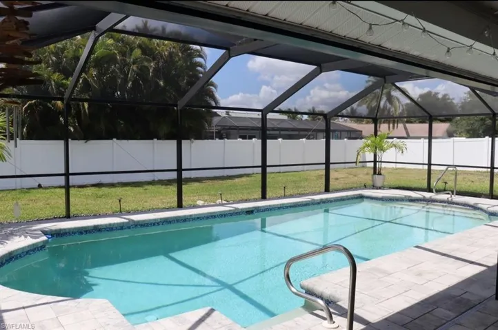 View of pool with glass enclosure, a fenced in pool, a fenced backyard, and a yard