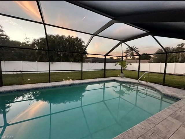 Oversized pool with vaulted pool cage, completely surrounded by privacy fence.