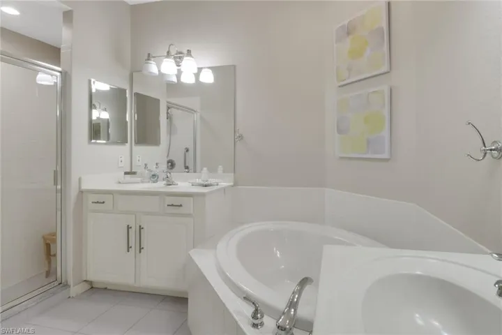 Bathroom featuring independent shower and bath, vanity, and tile patterned floors