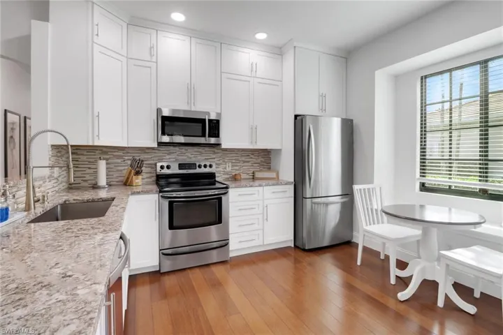 Kitchen featuring light stone countertops, white cabinetry, appliances with stainless steel finishes, and sink