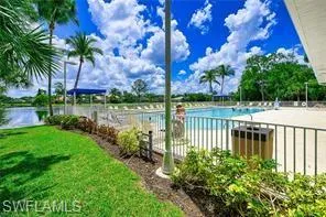 Community pool featuring a lawn, a water view, and fence
