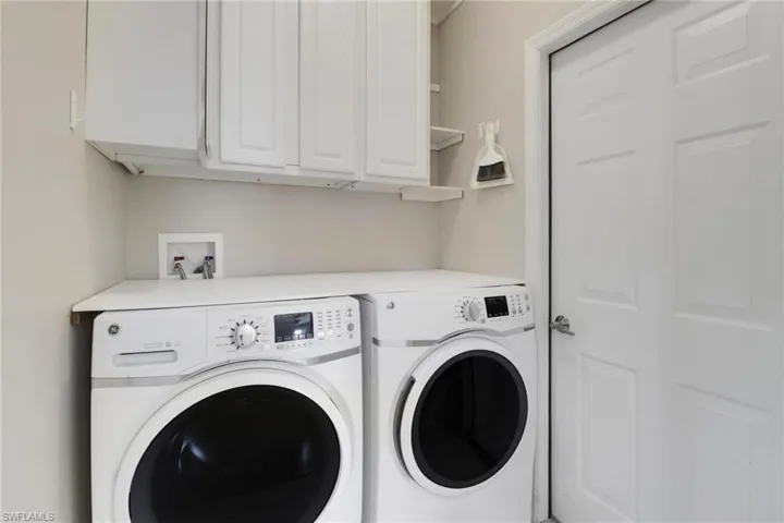 Washroom featuring cabinets and washing machine and dryer