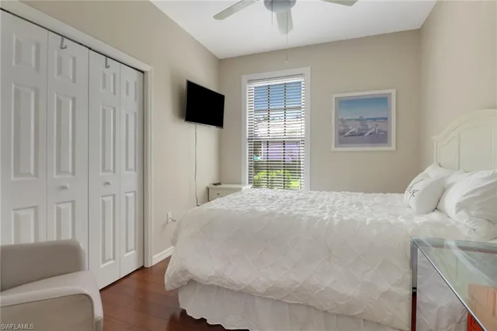 Bedroom with dark wood-type flooring, ceiling fan, and a closet