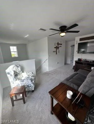 Living area featuring carpet flooring and ceiling fan