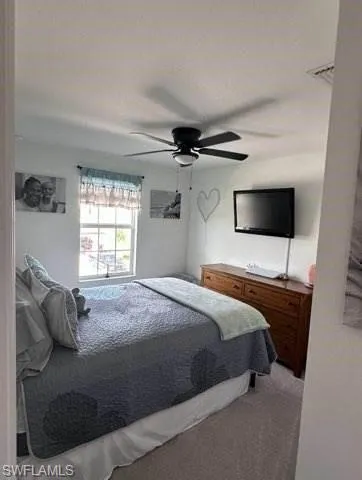 Bedroom with a ceiling fan and light carpet