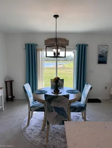 Dining space with suspended lighting and light tile patterned floors
