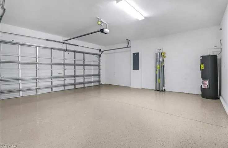 Garage featuring electric water heater, electric panel, and water heater
