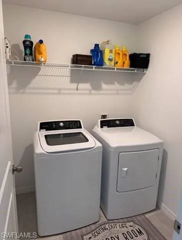 Laundry area featuring washing machine and clothes dryer and baseboards