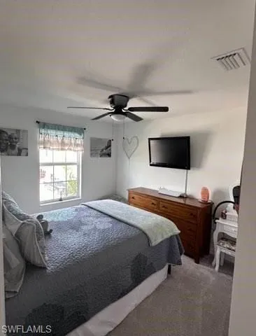 Carpeted bedroom with a ceiling fan